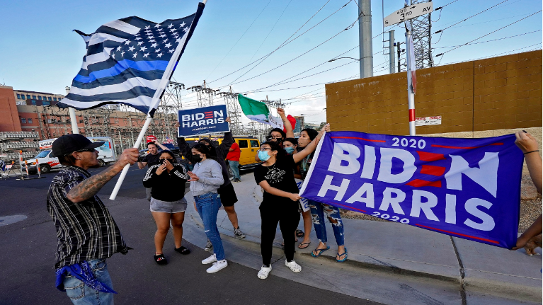 Pro Trump supporter, left, confronts pro Biden supporters at a rally outside the Maricopa County Recorder's Office, Saturday, Nov. 7, 2020, in Phoenix. President-elect Joe Biden defeated President Donald Trump on Saturday to become the 46th president of the United States. (AP Photo/Matt York)