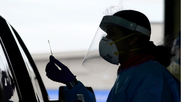 A person in PPE administers a COVID-19 test at a drive-thru site (AP Image/File)