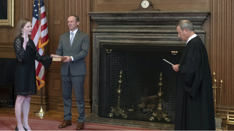 In this image provided by the Collection of the Supreme Court of the United States, Chief Justice John G. Roberts, Jr., right, administers the Judicial Oath to Judge Amy Coney Barrett in the East Conference Room of the Supreme Court Building, Tuesday, Oct. 27, 2020, in Washington as Judge Barrett's husband, Jesse M. Barrett, holds the Bible. (Fred Schilling/Collection of the Supreme Court of the United States via AP)