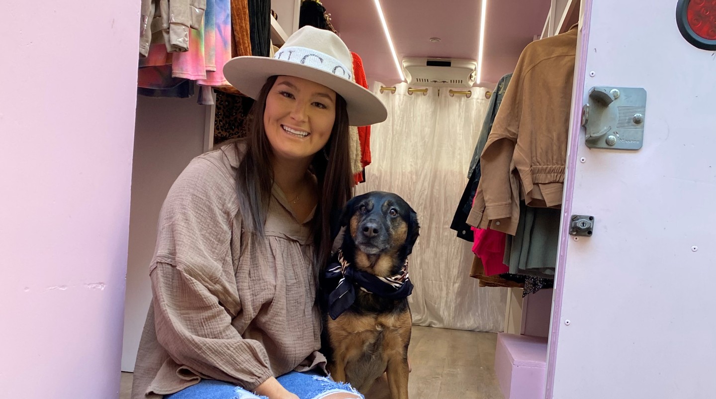 Kendall Cox sits with her dog Stella inside her mobile truck boutique. (Spectrum News 1)